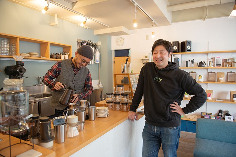 本社に程近い喫茶店で店主と談笑する齋藤さん=宮崎市